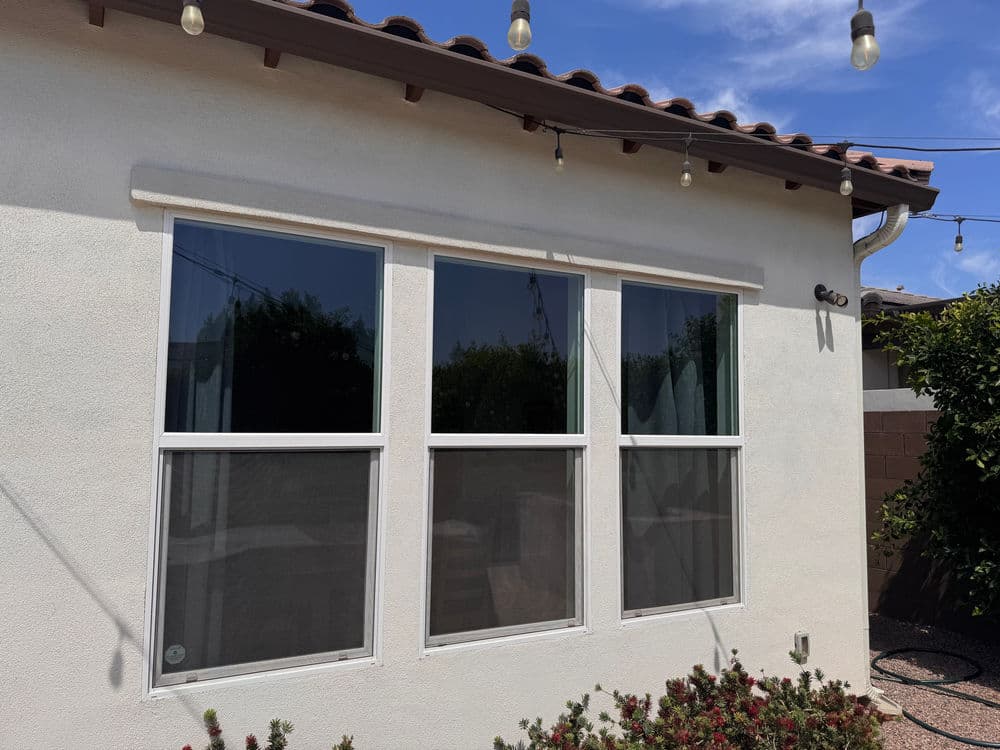 Exterior view of a home with three large windows and outdoor string lights.